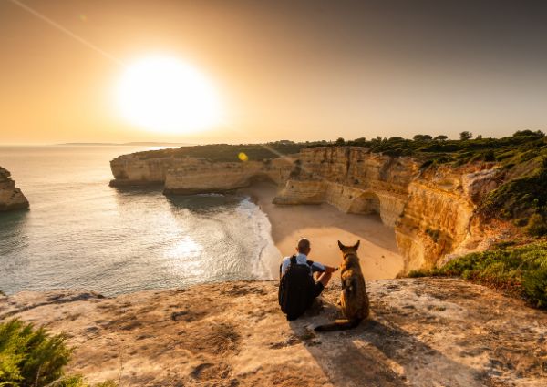 place holder picture of a man and a dog looking at the sunset above a cliff